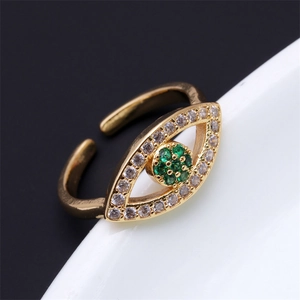Gros plan d'une bague Evil Eye dorée avec zircons blancs et pierre centrale verte