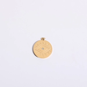 Macro shot of gold-plated eye pendant with zircon center and sunburst engraving