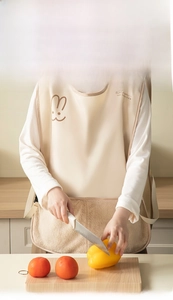 Detail of waterproof beige apron with bunny print and large pockets in kitchen setting