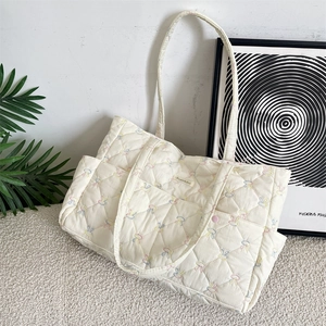 Detailed close-up of quilted floral tote bag featuring colorful rabbit embroidery patterns