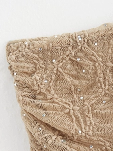 Vue macro du tissu en dentelle abricot avec sequins pour l'ensemble jupe plissée