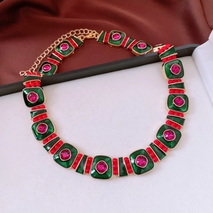 Detail of vintage necklace with green enamel squares and red beads on gold chain