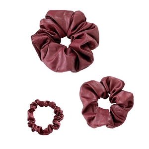 Three-piece set of burgundy leather scrunchies in various sizes on white backdrop