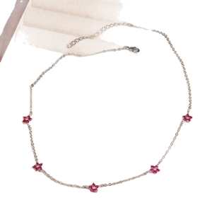 Silver fashion necklace with five colorful red flower rhinestones on a beige fabric