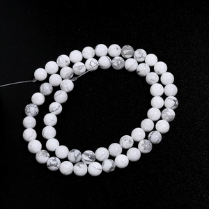 Macro shot of white turquoise beads with grey veins on a matte black background