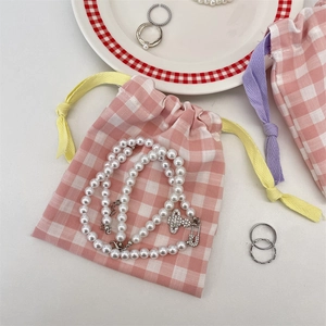 Detailed view of Saturn-shaped orb pendant necklace with pink checkered drawstring gift bag
