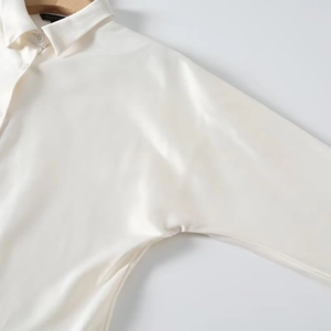 Detailed view of the neckline on a white satin blouse with elegant pearly silk texture