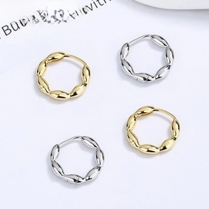 Flat lay of twisted 925 silver and gold hoop earrings on a clean white background