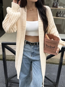 Cardigan lungo beige da donna in maglia grossa con crop top bianco e jeans blu