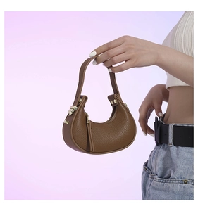 Detailed close-up of brown crescent bag featuring premium litchi texture and gold hardware