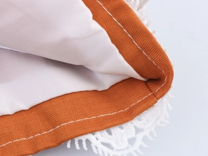 Close-up of elegant orange canvas blazer with white lace trim and fine stitching
