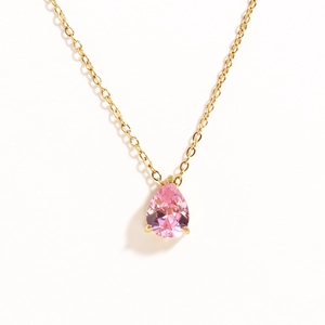 Close-up of gold chain necklace featuring a pear-shaped pink zircon pendant on white background