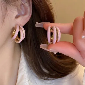 Orecchini a cerchio intrecciati rosa e oro indossati da modella per un look elegante