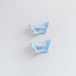 Detailed macro view of two light blue matte butterfly-shaped hollow metal BB hair clips