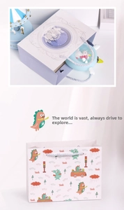 Detailansicht von Cartoon-Geschenktüten aus Papier mit Riesenrad- und Dino-Motiven und Kordelgriff