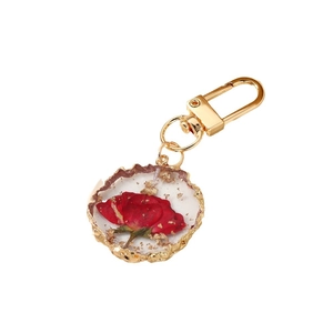 Golden resin keychain with red dried rose petals and gold foil inside round pendant