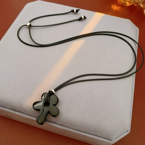 Macro detail of cross pendant made of tiger eye stone on adjustable black cord necklace