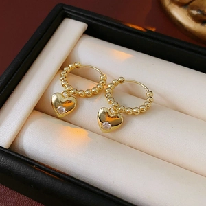 Dettaglio macro di orecchini a cuore placcati oro con zirconi in una scatola regalo