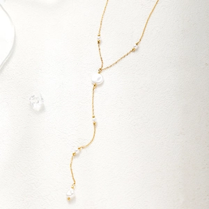 Close-up of gold-plated stainless steel Y-necklace with elegant white pearls and tassels