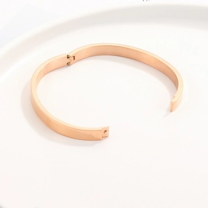 Close-up of rose gold stainless steel bangle with polished finish and hinge closure
