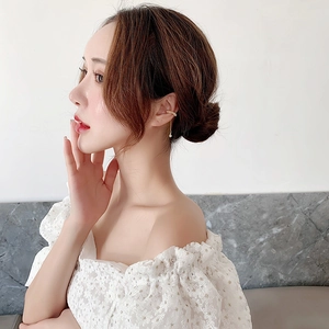 Detail of elegant gold ear cuff with long chain tassel and white pearl on a female model