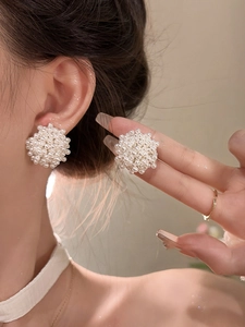 Close-up detail of elegant white pearl cluster earrings worn on ear showing 3D texture