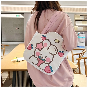 Detail of canvas tote bag featuring cute cartoon rabbit and peach graphics with pink straps