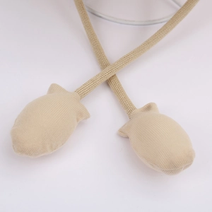 Detailed macro view of beige knitted hat straps with cute small glove-shaped decorations