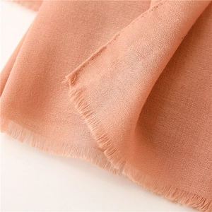 Detalle macro de bufanda rosa naranja con textura de lino y algodón y flecos delicados
