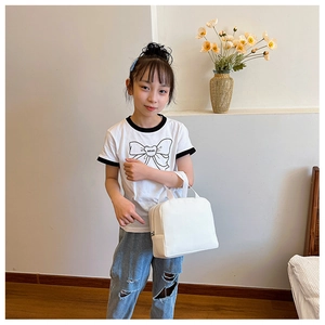 Close-up of white canvas lunch bag held by a girl in a cozy minimalist home setting