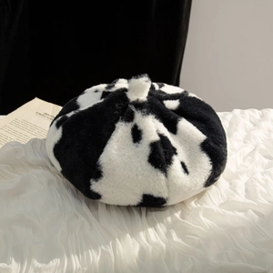 Close-up of the soft black and white cow print plush texture on a stylish beret hat