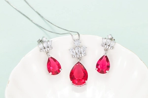 Détail du collier couronne et boucles d'oreilles rubis rouge sur plateau blanc
