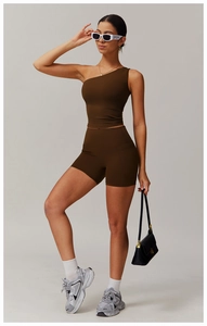 Detail of dark brown one-shoulder sports bra and high-waisted shorts on a fitness model