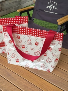Detail of red cherry and dog pattern on waterproof PVC tote bag with snap button closure