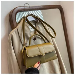Détail d'un sac à main minimaliste en cuir vert moutarde avec rabat triangulaire sur cintre