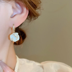 Close-up of model wearing gold-plated camellia flower earrings with zircon details