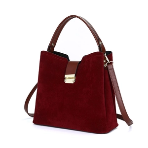 Burgundy suede shoulder bag with brown leather handles and golden metal hardware on white