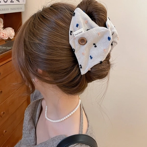 Detail of light grey pleated fabric hair tie with mini embroidery and handmade tag
