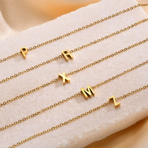 Gold plated titanium steel alphabet pendant necklaces with 26 letters on a silk background