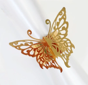 Close-up of golden butterfly napkin ring featuring intricate hollow metal engraving
