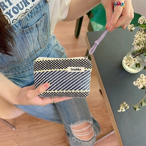 Close-up of a woven striped cosmetic bag with multi-color geometric patterns and zipper