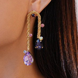 Close-up of golden twisted rope earrings with purple pear-shaped crystals on model