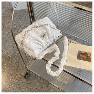 Close-up of white bubble pleated bag with metal chain strap on a modern trolley