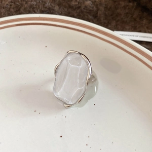 Close-up of silver ring with large translucent white resin stone on white ceramic plate