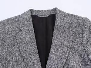 Close-up of gray tweed blazer texture with notched lapel and high-quality stitching detail