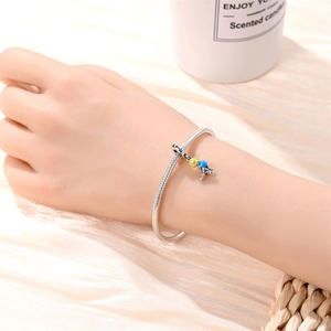 Detail of silver snake chain bracelet with astronaut charm and colorful enamel accents