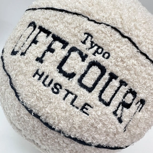 Close-up of off-court plush basketball pillow with soft cream fabric and black embroidery