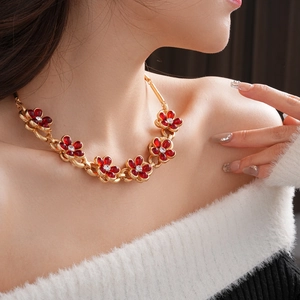 Close-up of vintage golden necklace featuring intricate red flower petals with crystal centers