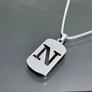 Close-up of silver titanium steel necklace featuring a hollow letter N pendant on a box chain