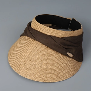 Detail of woven straw sun visor with coffee fabric bow and gold oval metal plate